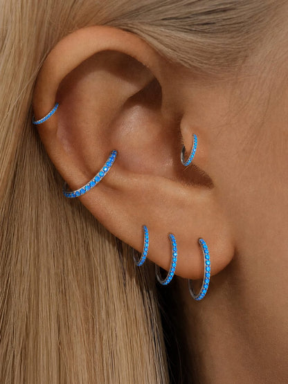 Blue opal titanium clicker hoops worn in helix cartilage and lobe piercings