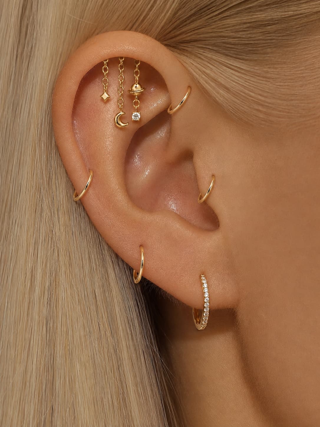 Gold tone moon and planet hidden helix earring styled in a curated ear stack