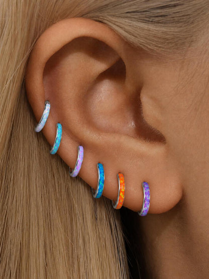 Colorful opal titanium clicker hoops styled across multiple lobe and helix piercings.