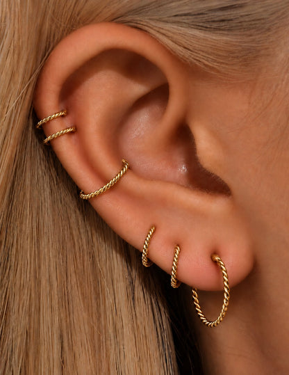 Gold G23 titanium twisted clicker hoops worn in a curated multi-piercing ear stack