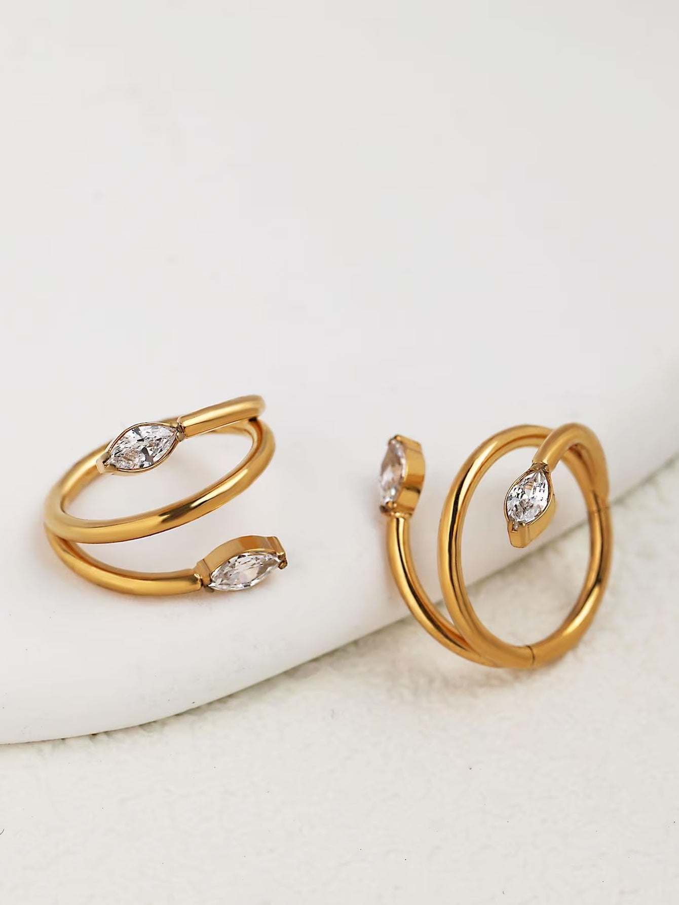 Close-up of gold marquise crystal double clicker hoops on a white surface