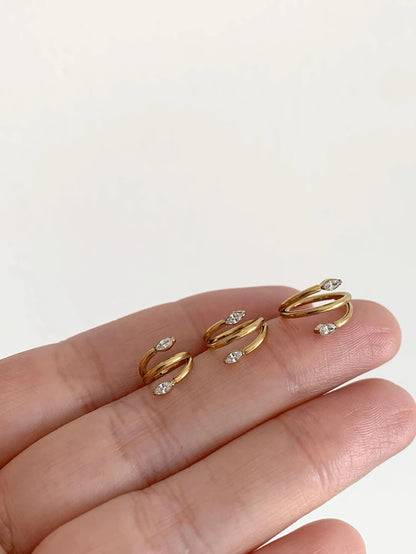 Three sizes of gold marquise CZ titanium clicker hoops held on fingertips