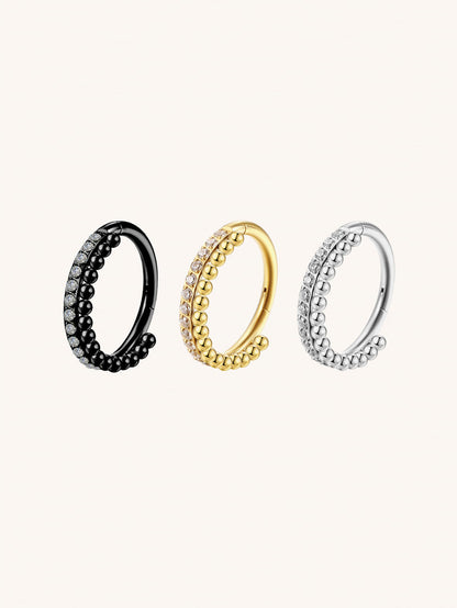 Gold silver and black CZ beaded clicker hoop rings on beige background