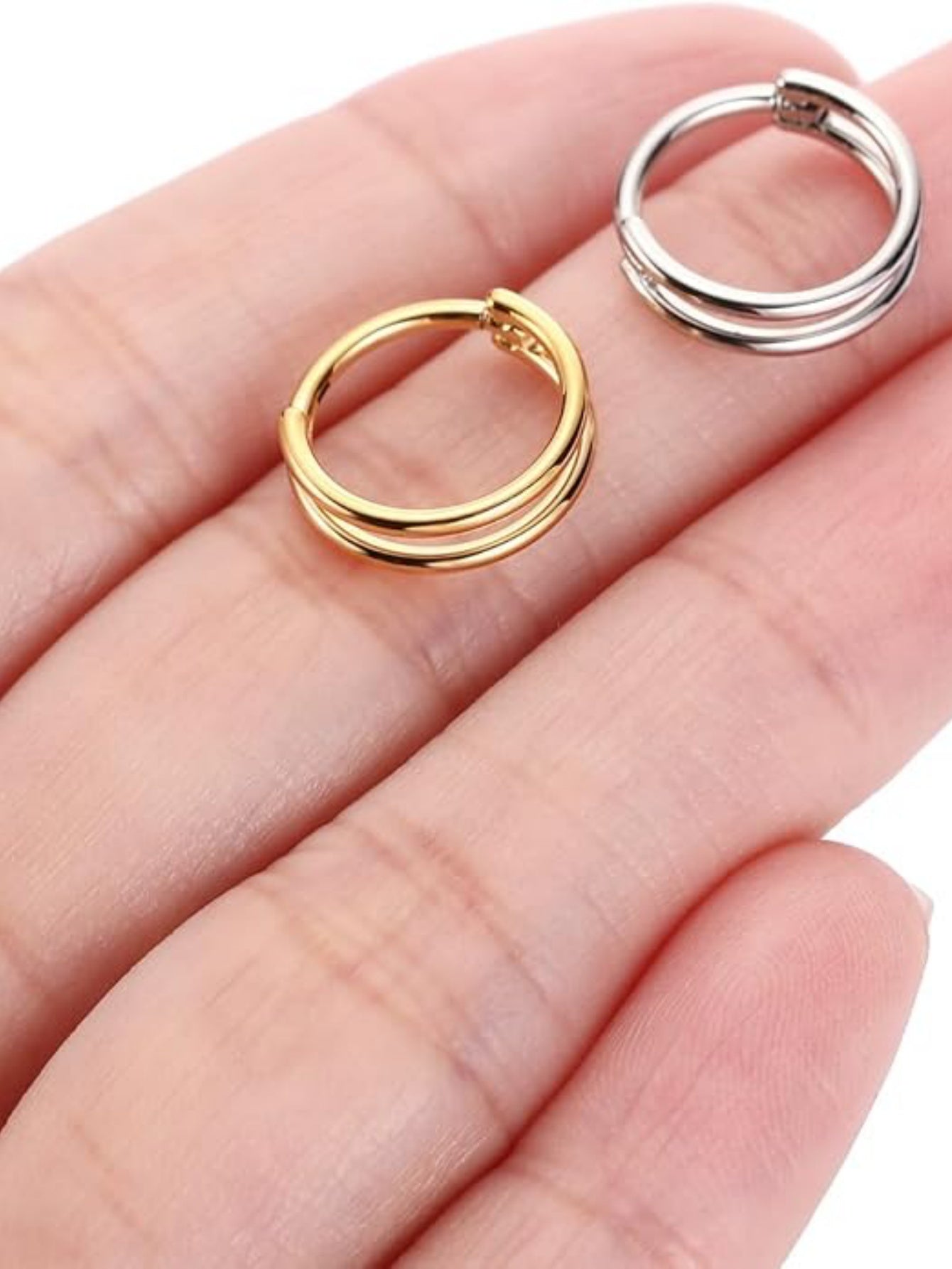 Gold and silver titanium double hoop clicker rings shown on hand