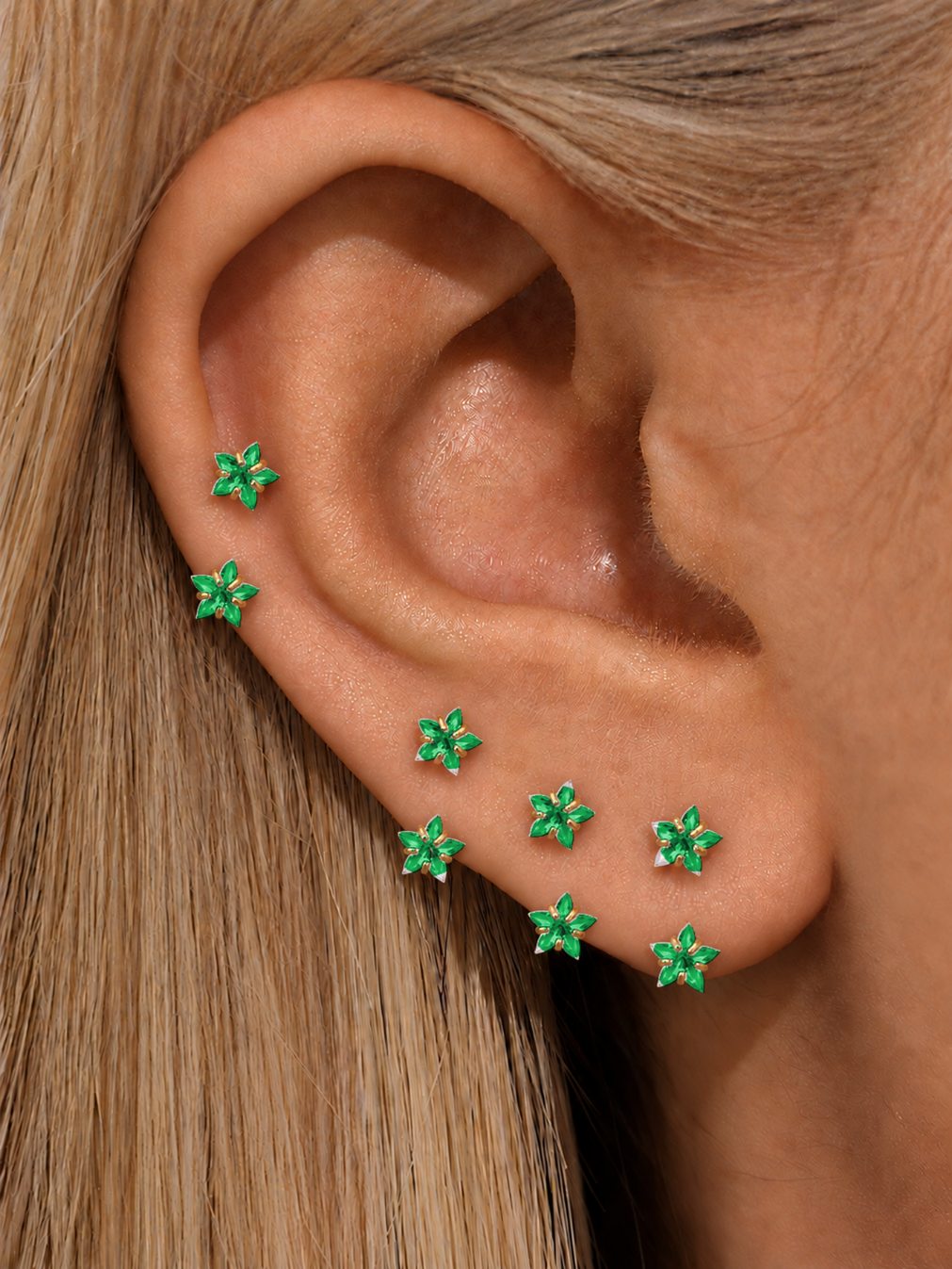 Green double star horseshoe rings styled across helix and lobe piercings