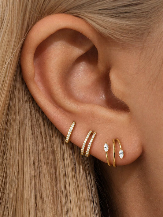Gold G23 titanium 3-piece CZ ear stack worn on the earlobe with pavé clicker, double-row hoop and marquise CZ spiral hoop.