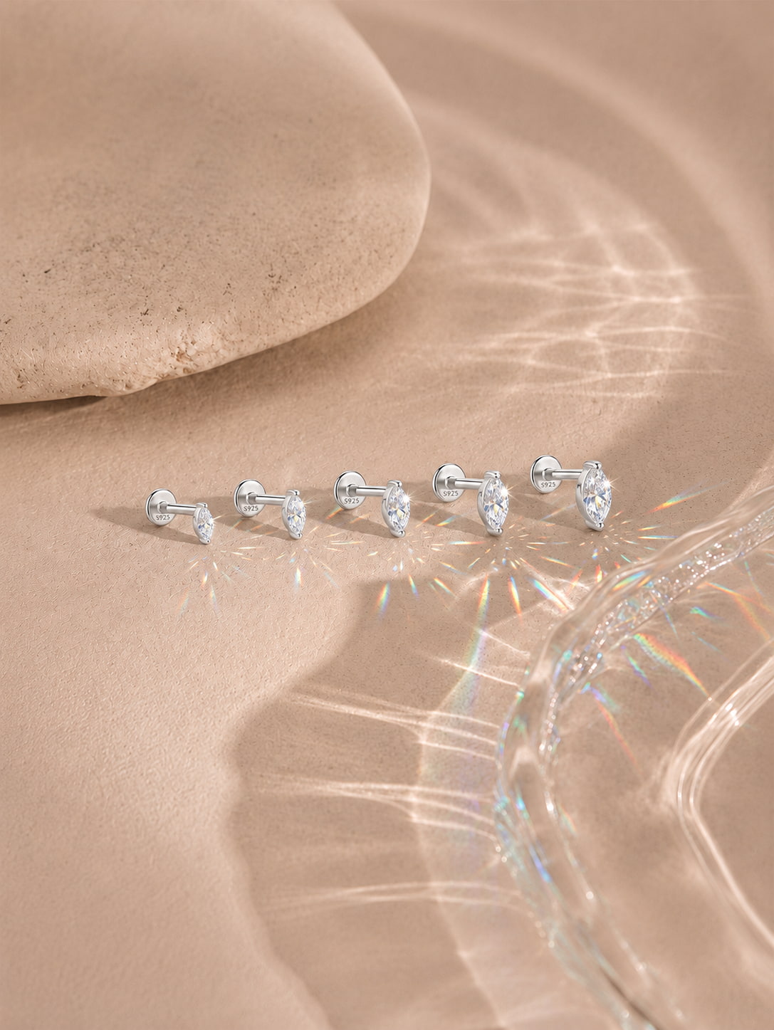 Marquise moissanite flat back studs in five sizes on a warm neutral background
