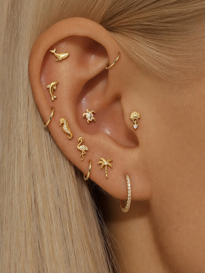 Gold ocean-inspired ear stack with whale, dolphin, seahorse, flamingo, palm tree, turtle and seashell flat back earrings