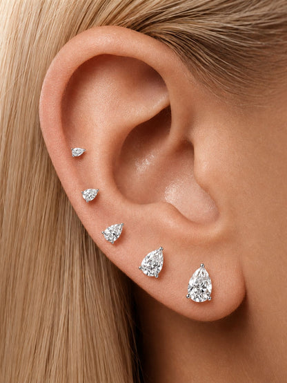 Pear-cut moissanite flat back studs styled in graduated sizes on the ear