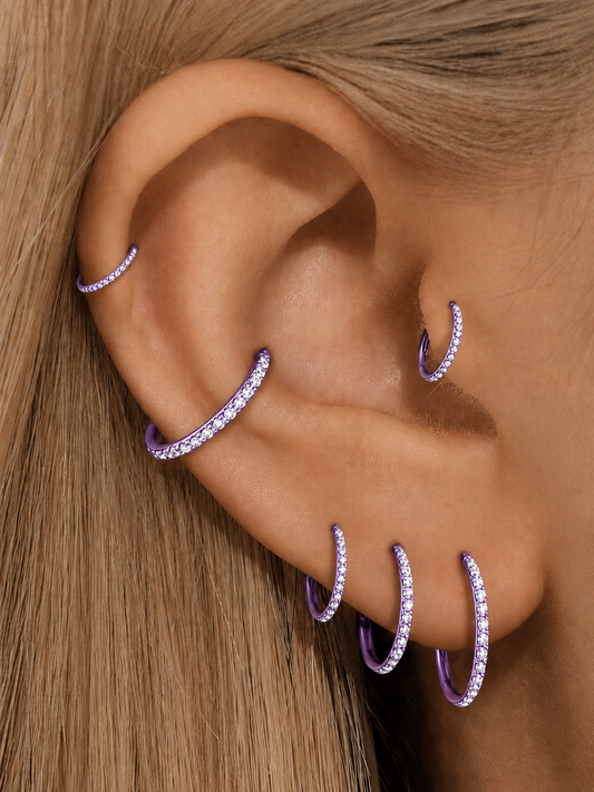 Purple titanium clicker hoops with clear CZ stones styled on helix conch lobe and tragus piercings