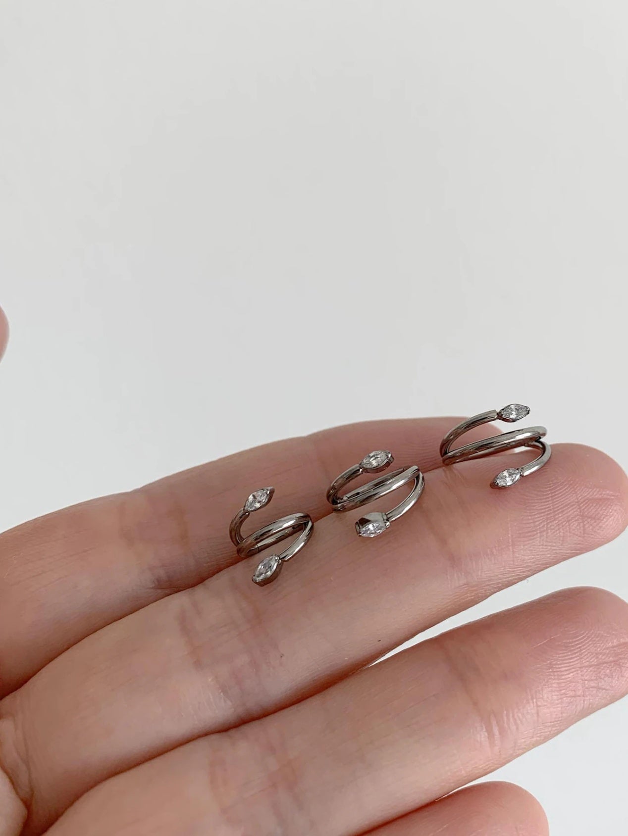 Silver marquise CZ titanium clicker hoops displayed in three sizes