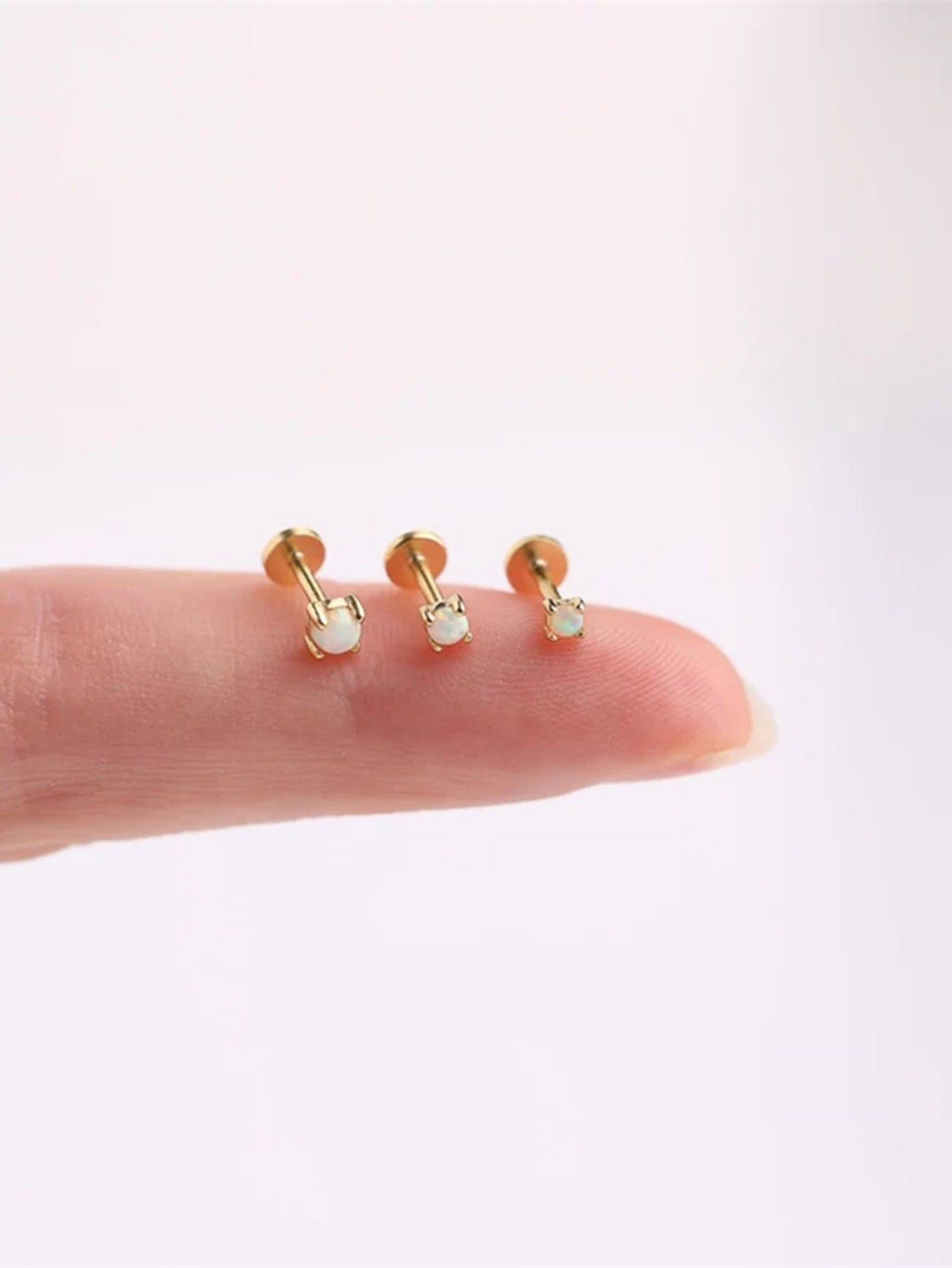 Tiny 925 sterling silver opal flat back stud earrings shown on fingertip for size reference